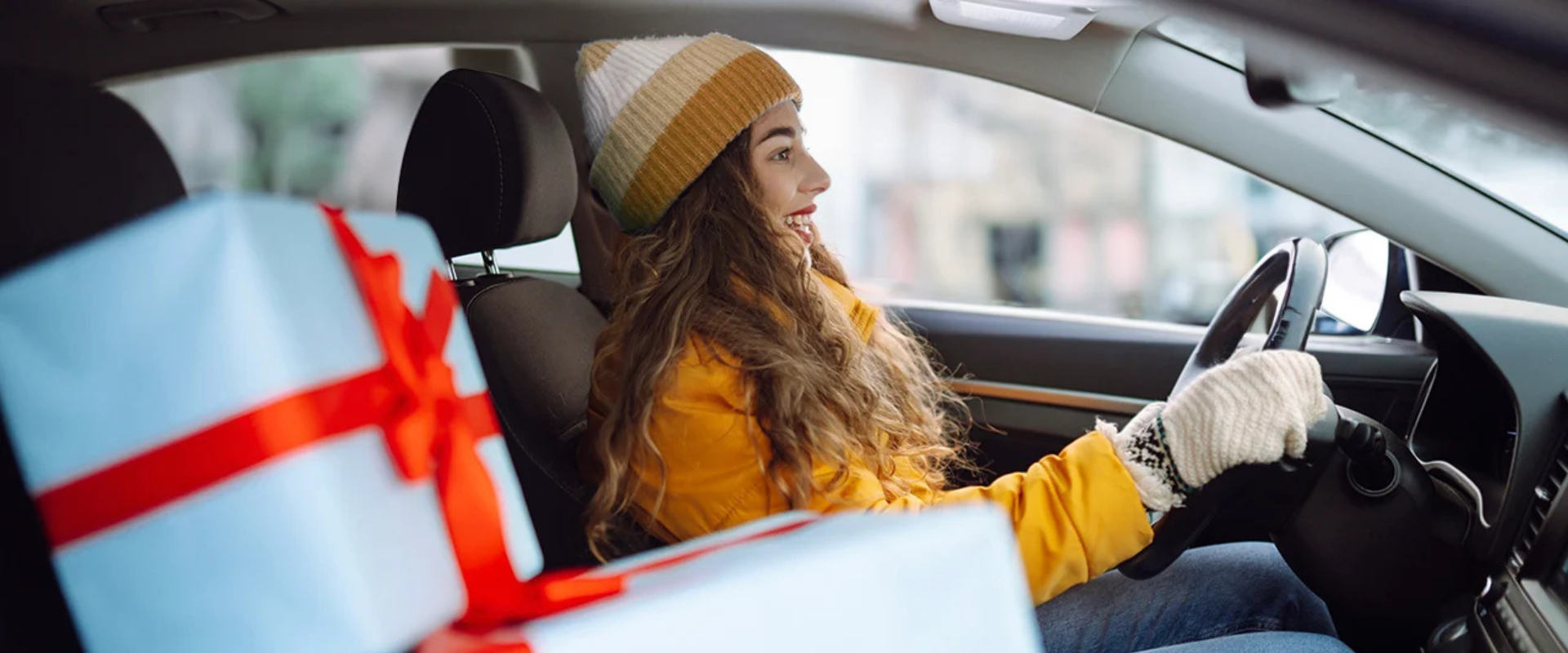 Mujer sonriente conduciendo un auto con regalos navideños, lista para disfrutar de sus vacaciones Guatemala